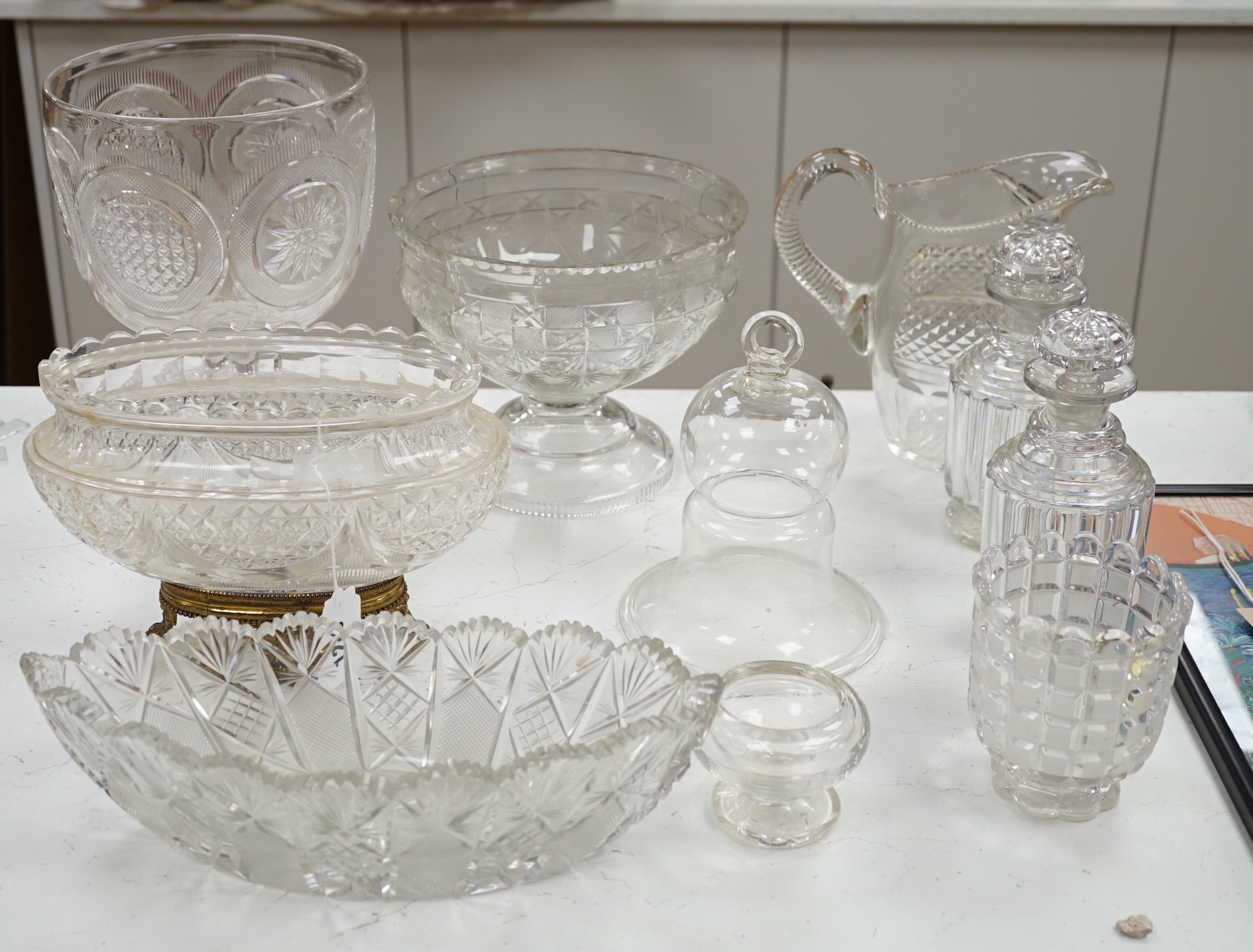 An early 20th century oval cut glass bowl on gilt metal stand, a pair of slice cut decanters and stoppers, a blown glass smoke bell two bowls and four other items of glassware, tallest 26 cm